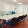 Salle avec table, chaises, tableau blanc, porte jaune et extincteur.