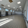 Salle vide avec carrelage, fenêtres, portes, radiateurs et éclairage au plafond.