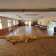 Salle avec parquet, tables, chaises, et rideaux.