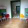Salle d'attente avec chaises colorées, tables basses, panneaux d'affichage et porte verte.