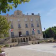 Grande bâtisse avec drapeaux, cour et arbres.