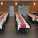 Salle de banquet avec tables, chaises, nappes, vaisselle et fleurs.