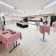 Salle avec tables à nappes à carreaux, nourriture, tables hautes, porte-manteaux.