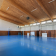 Salle de sport avec panier de basket, murs en bois, sol bleu.