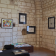 Salle d'exposition avec murs en pierre, tableaux, vitrine et table avec brochures.