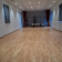 Salle vide avec parquet, tables, chaises et rideaux.