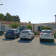 Parking avec trois voitures, lampadaire et maison en arrière-plan.