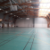 Gymnase avec paniers de basket, filet de volley-ball, gradins et éclairage.