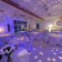 Salle de réception avec tables, chaises, luminaires et déco lumineuse.