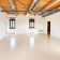 Pièce vide avec sol lisse, plafond en bois, fenêtres et radiateur.