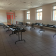 Salle avec tables, chaises, extincteur, porte rouge et fenêtres.