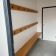 "Vestiaire avec banc, patères et porte dans un couloir."