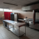 Cuisine avec tables en acier inoxydable, fours, plaques de cuisson, hotte, réfrigérateur et évier.
