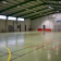 Gymnase avec paniers de basket, terrain de handball et portes orange de sécurité.