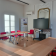 Salle de réunion avec tables, chaises, écran, climatiseur, miroir et affiche.