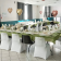 Salle avec tables, chaises, nappes, verres, couverts, ballons en forme de coeur.