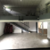 Salle vide avec escalier, mezzanine, portes et fenêtres. Chaises empilées près de l'escalier.