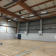 Salle de sport avec paniers de basket, terrain de jeu, panneau d'affichage et projecteurs.