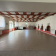 Salle spacieuse avec sol carrelé, murs blancs, plafond en bois, portes et fenêtres.