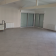 Salle vide avec portes vitrées, radiateurs et sol carrelé.