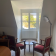 Pièce avec deux chaises, table ronde, radiateur, fenêtre, porte et lampe sur pied.