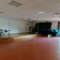 Salle vide avec tables, chaises, rideau, tableau, projecteur et extincteur.