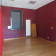 Pièce vide avec porte, fenêtre, rideau rouge, porte en bois et sol en parquet.