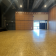 Salle spacieuse avec plancher en bois, murs en bois, éclairage au plafond, rideau de scène, portes vitrées et systèmes audio/son.