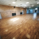 Salle vide avec parois en bois, sol en parquet, portes, extincteur et climatiseur.