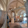 Salle voûtée avec piliers, vitraux, lustres, tentures et œuvres d'art.