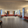 Salle de réunion avec tables, chaises, tableau, éclairage mural et plafonnier.