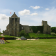 Ruines de château avec tour, voiture, aire de jeux et terrain herbeux.