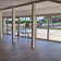 Salle vide avec portes vitrées, chaises et sol en bois.
