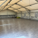 Salle spacieuse avec parquet, bancs, et fenêtres.