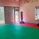 Salle avec tapis vert, deux poire de boxe et fenêtres fermées.
