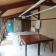 Salle avec tables, chaises, tableau blanc, frigo, étagères et fenêtres.
