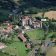 Village médiéval avec château, maisons, routes, voitures et champs.