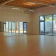 Salle de danse avec parquet, barres, grandes fenêtres et murs en brique.