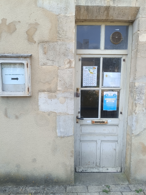 Porte blanche avec vitre, boîte aux lettres et affiches.