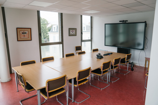 Salle avec table, chaises, écran, tableau.