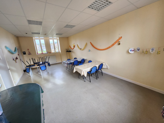 Salle avec tables, chaises, décoration murale, fenêtres et rideaux.