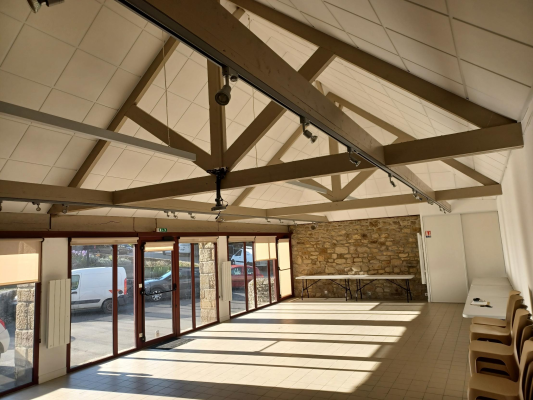 Salle avec poutre, sol carrelé, fenêtres, voiture dehors.