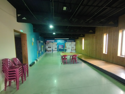 Salle spacieuse avec chaises, tables, murs colorés et fenêtres.