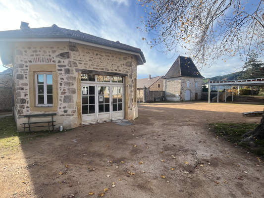 Bâtiment en pierre avec porte, fenêtre, banc et cour.