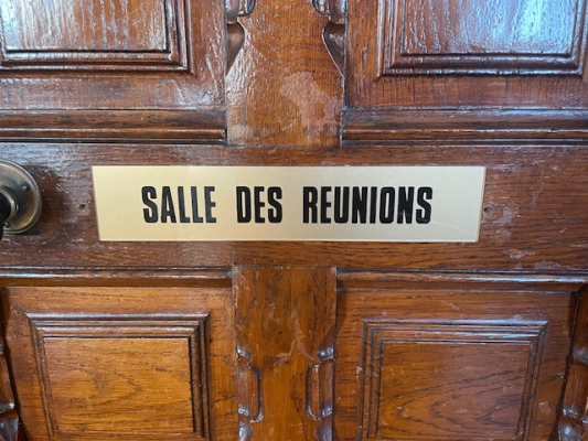 Porte en bois avec une pancarte "Salle des Réunions" et une poignée.