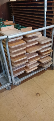 Chariot métallique avec piles de tables en bois.