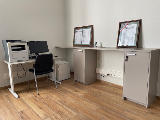 Bureau avec ordinateur, imprimante, chaise, classeurs, étagère et cadres.