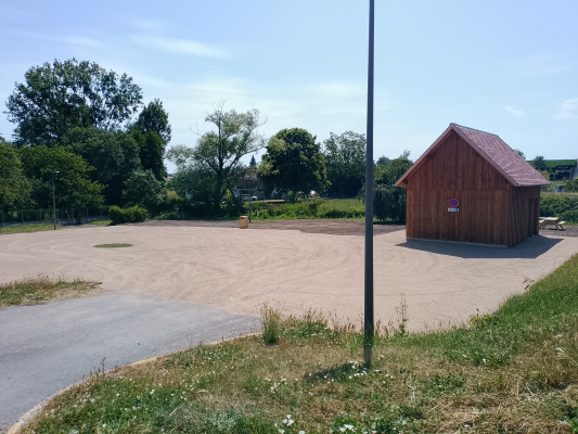 Terrain de beach volley avec cabane en bois et poteau.