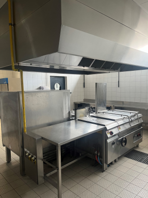 Cuisine professionnelle avec plans de travail, fours, plaques de cuisson, hottes et équipements de cuisine en acier inoxydable.