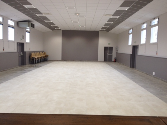 Salle vide avec rangée de chaises, projecteur, portes et fenêtres.